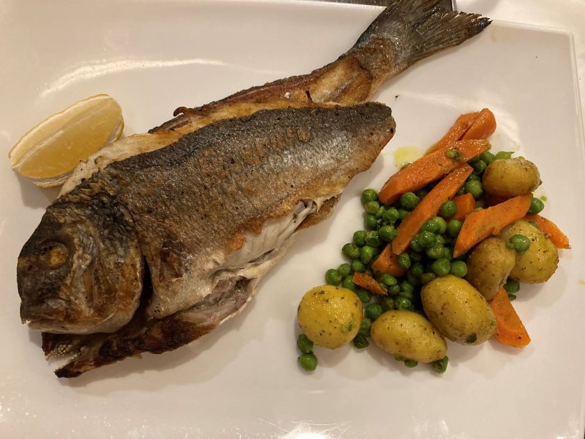 Grilled Sea Bream with Vegetables on a white plate